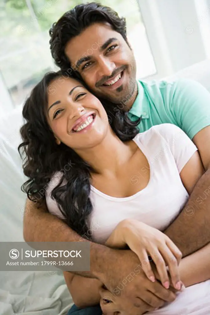 Couple in living room embracing and smiling (high key)
