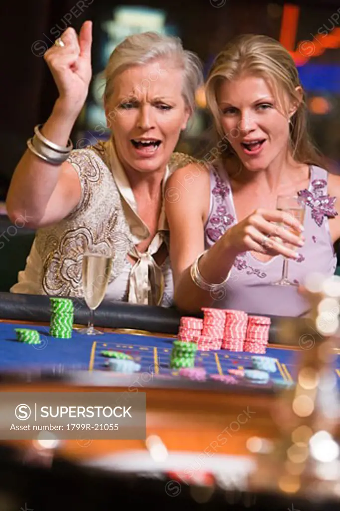 Two women in casino playing roulette and smiling (selective focus)