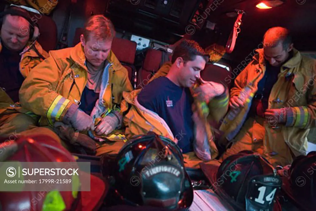 Four firemen in fire engine putting on gear (blur)