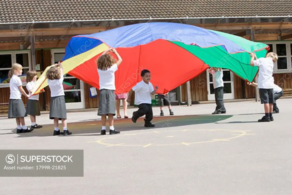 Students outdoors during recess playing with a parachute