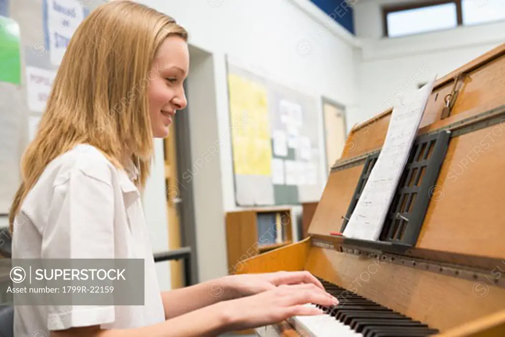 Female student learning piano in classroom