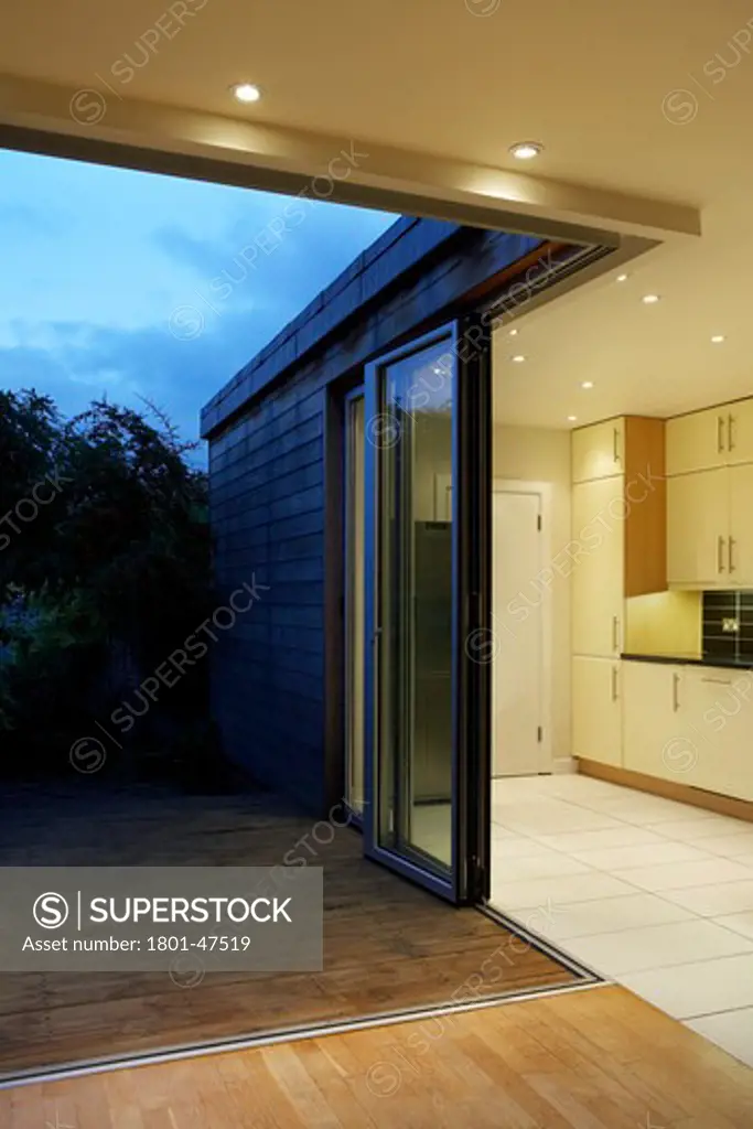 Private House, London, United Kingdom, Archicraft, PRIVATE HOUSE ARCHICRAFT ROB MATHISON SOUTH WOODFORD LONDON UK 2009. INTERIOR SHOT SHOWING THE SLEEK DESIGN OF THE OPEN PLAN KITCHEN AND GLASS DOOR ONTO THE GARDEN LIT BY NIGHT