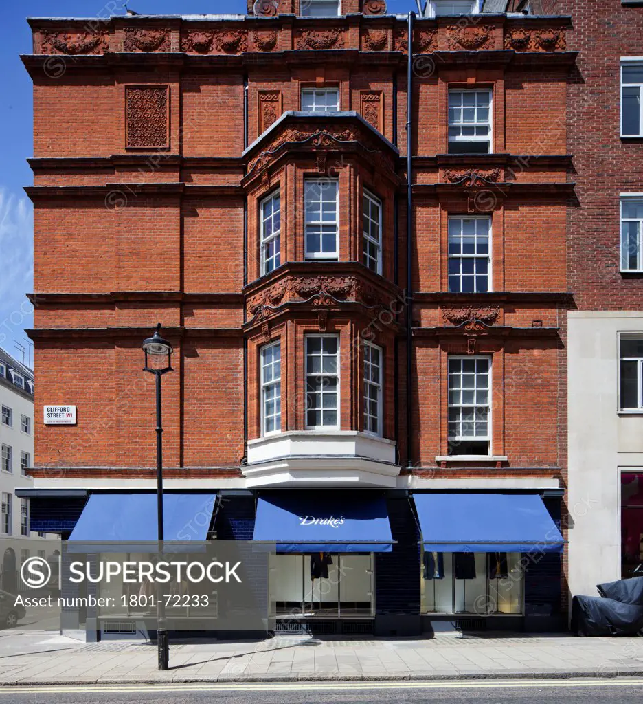 Drake's, London, United Kingdom. Architect William Russell, 2011. Exterior frontage of Drake's store on Clifford Street with blue awnings.