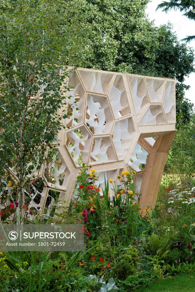 Times Eureka Pavilion, Kew, United Kingdom. Architect NEX, 2011. Exterior detail of wall and entrance with flower bed.