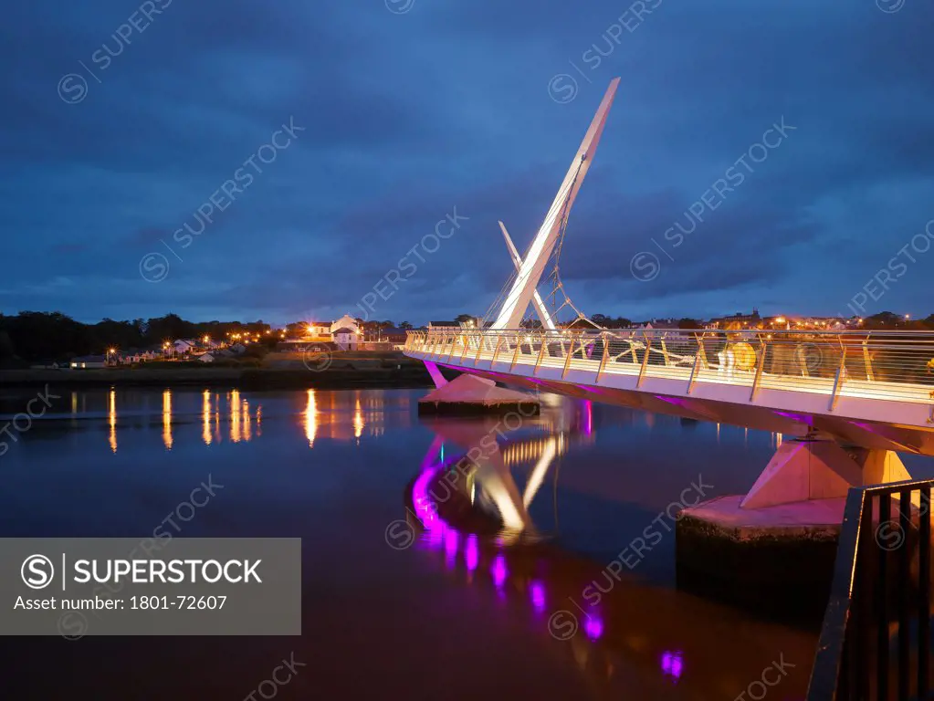 Peace Bridge, Derry, United Kingdom. Architect Wilkinson Eyre Architects, 2011. View from riverbank at dusk showing river.
