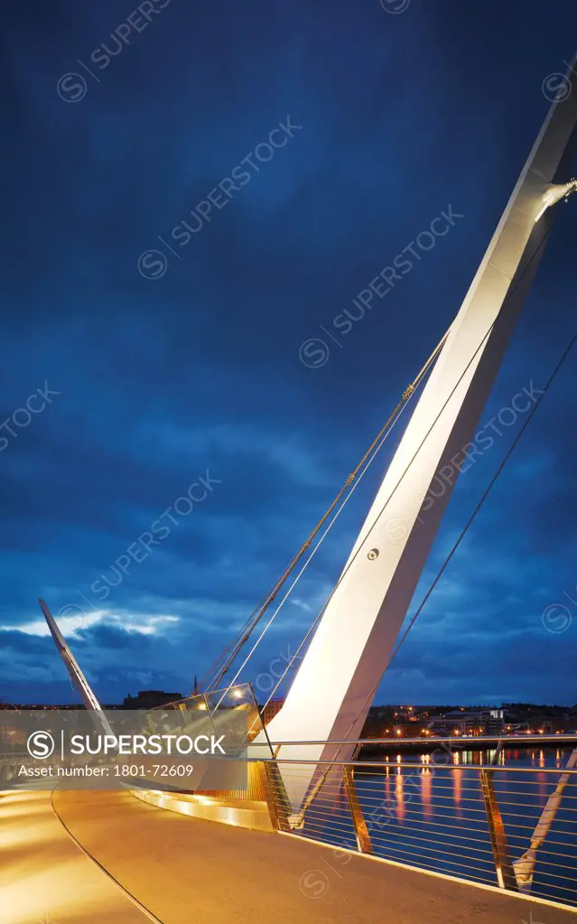 Peace Bridge, Derry, United Kingdom. Architect Wilkinson Eyre Architects, 2011. View on bridge at dusk showing steel support and walkway.