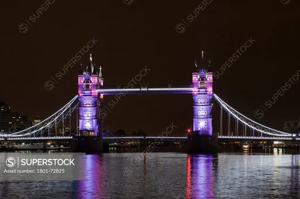 Tower Bridge Re-lighting, London, United Kingdom. Architect Horace Jones, 2012. View of Tower Bridge capturing new lighting system from HMS Belfast.  Silver and pink lighting.