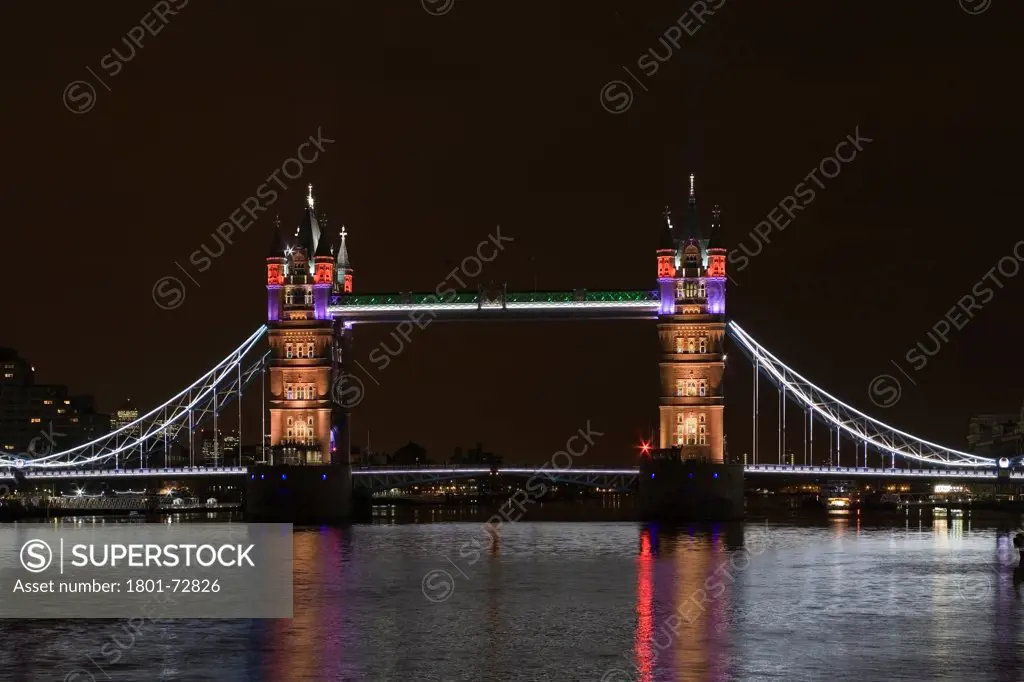 Tower Bridge Re-lighting, London, United Kingdom. Architect Horace Jones, 2012. View of Tower Bridge capturing new lighting system from HMS Belfast. Gold Lighting.