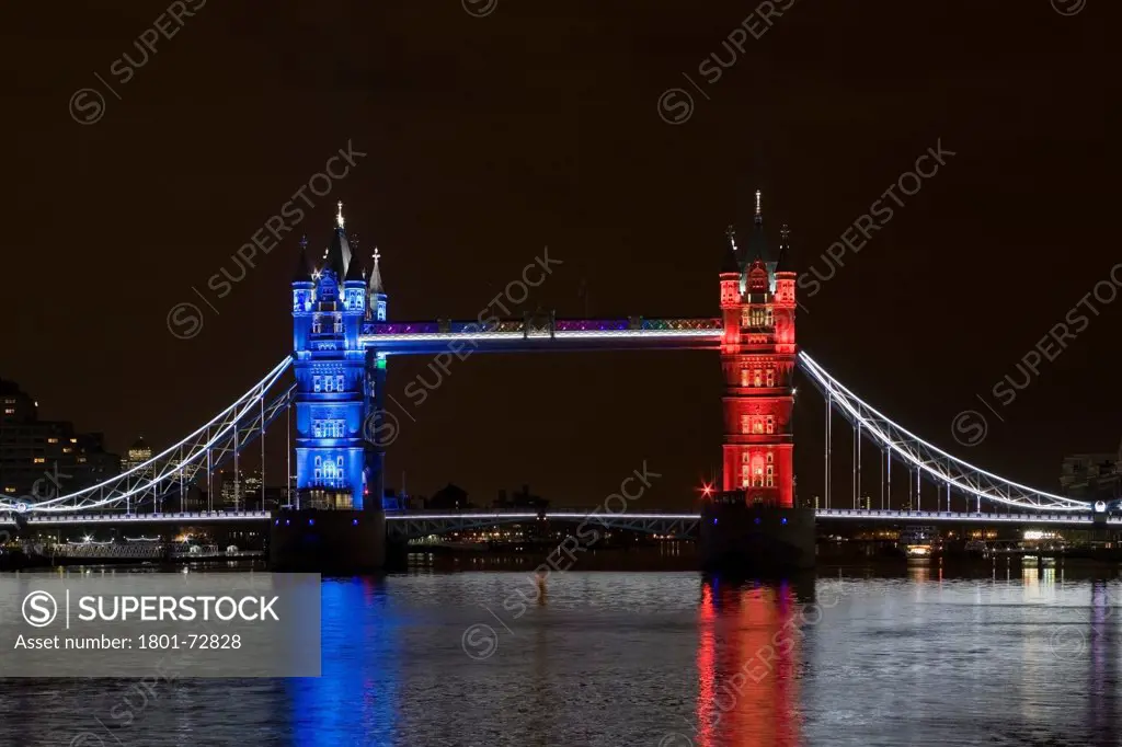 Tower Bridge Re-lighting, London, United Kingdom. Architect Horace Jones, 2012. View of Tower Bridge capturing new lighting system from HMS Belfast. Red, White, Blue Lighting.