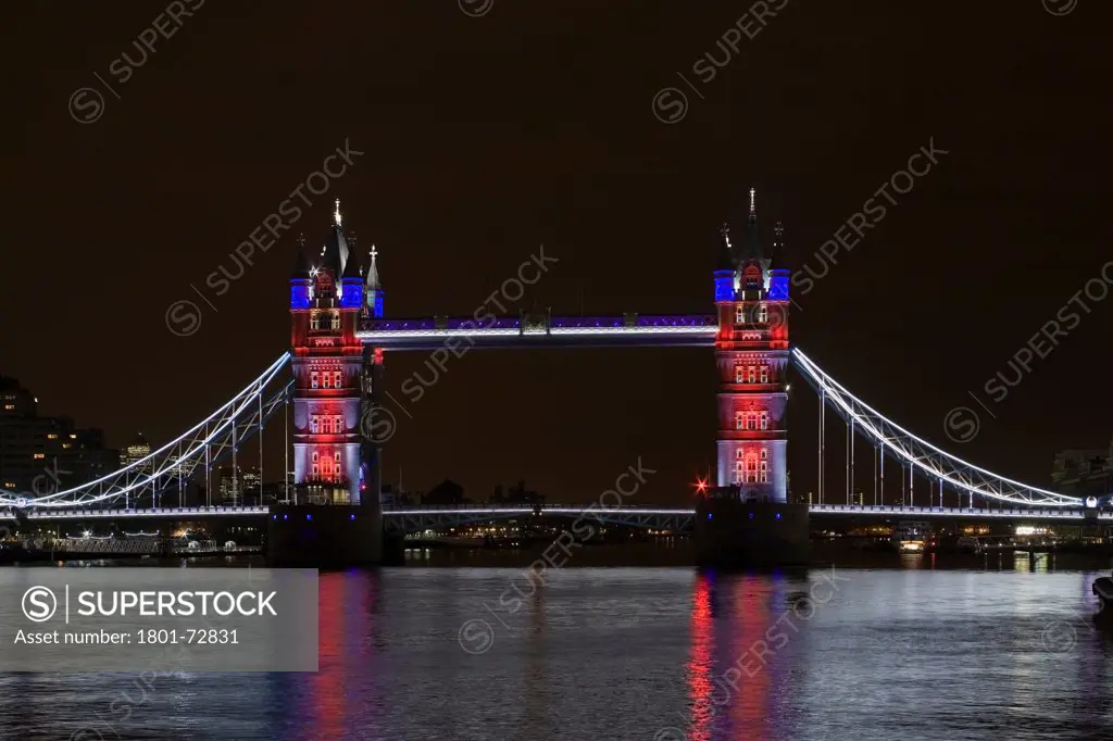 Tower Bridge Re-lighting, London, United Kingdom. Architect Horace Jones, 2012. View of Tower Bridge capturing new lighting system from HMS Belfast. Red, White, Blue Lighting.