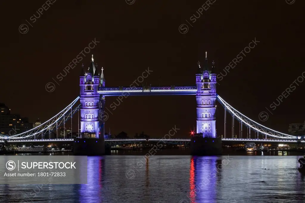 Tower Bridge Re-lighting, London, United Kingdom. Architect Horace Jones, 2012. View of Tower Bridge capturing new lighting system from HMS Belfast. Silver Lighting.