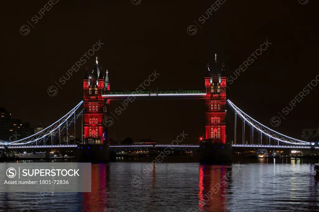 Tower Bridge Re-lighting, London, United Kingdom. Architect Horace Jones, 2012. View of Tower Bridge capturing new lighting system from HMS Belfast. Red Lighting.