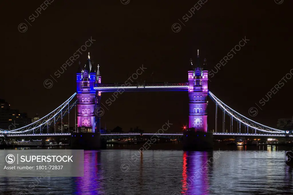 Tower Bridge Re-lighting, London, United Kingdom. Architect Horace Jones, 2012. View of Tower Bridge capturing new lighting system from HMS Belfast. Purple Lighting.