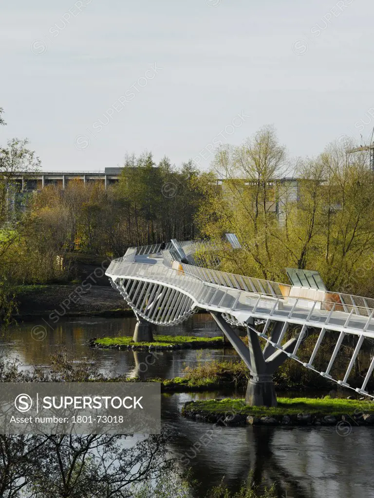 University of Limerick: Living Bridge, Limerick, Ireland. Architect Wilkinson Eyre Architects, 2007. View of bridge in context showing river and surrounding landscape.