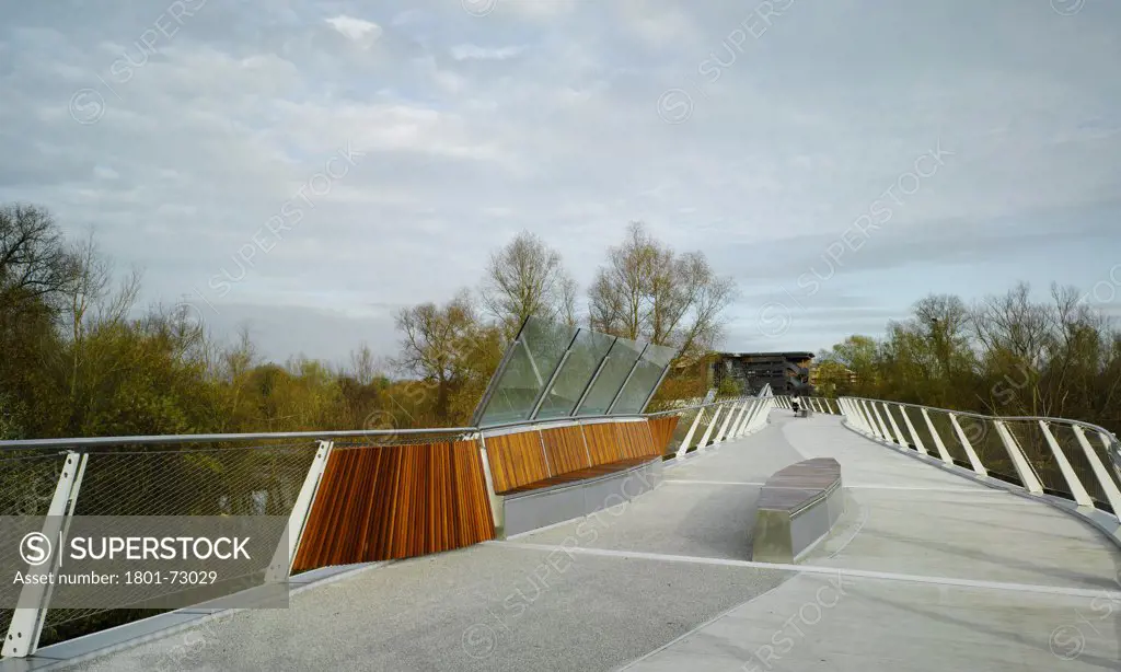 University of Limerick: Living Bridge, Limerick, Ireland. Architect Wilkinson Eyre Architects, 2007. View on bridge showing seating, surrounding landscape and adjacent buildings.