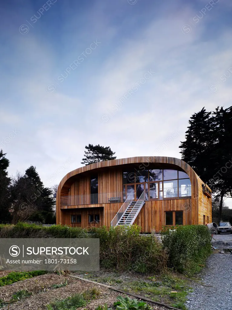 Ballynoe, Dublin, Ireland. Architect McCullough Mulvin, 2006. View from back garden showing stairs, balcony, timber cladding and surrounding landscape.