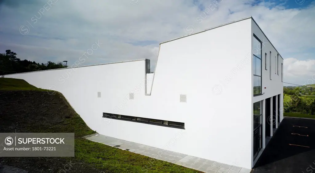 Westport Fire Station, Westport, Ireland. Architect McCullough Mulvin, 2007. View of North-East corner showing fire service entrance at lower level and the landscape sloping to the upper level.