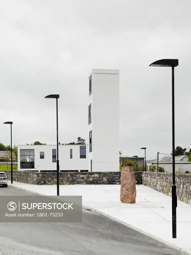 Westport Fire Station, Westport, Ireland. Architect McCullough Mulvin, 2007. View from North showing drill tower, stone wall and paved space with sculpture.