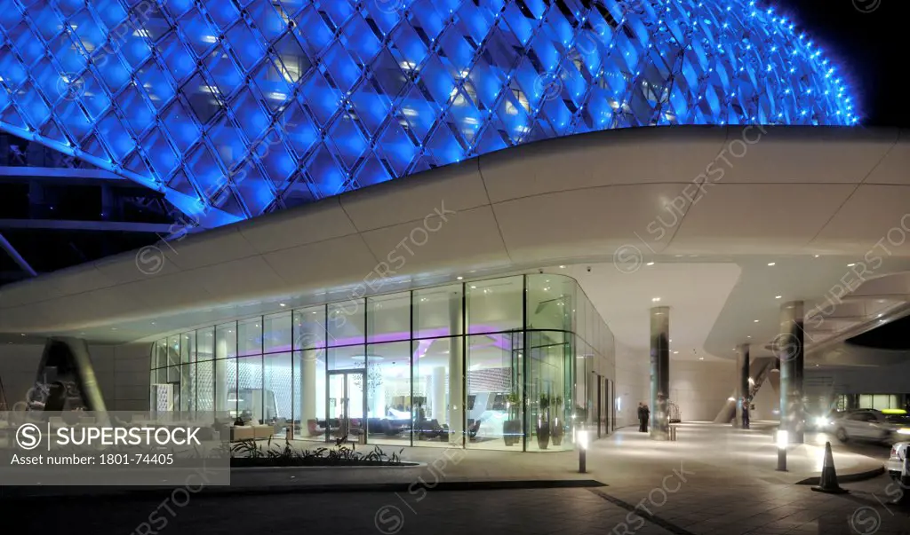Yas Hotel, Abu Dhabi, United Arab Emirates. Architect: Asymptote, Hani Rashid, Lise Anne Couture, 2010. Side view by night with car way.
