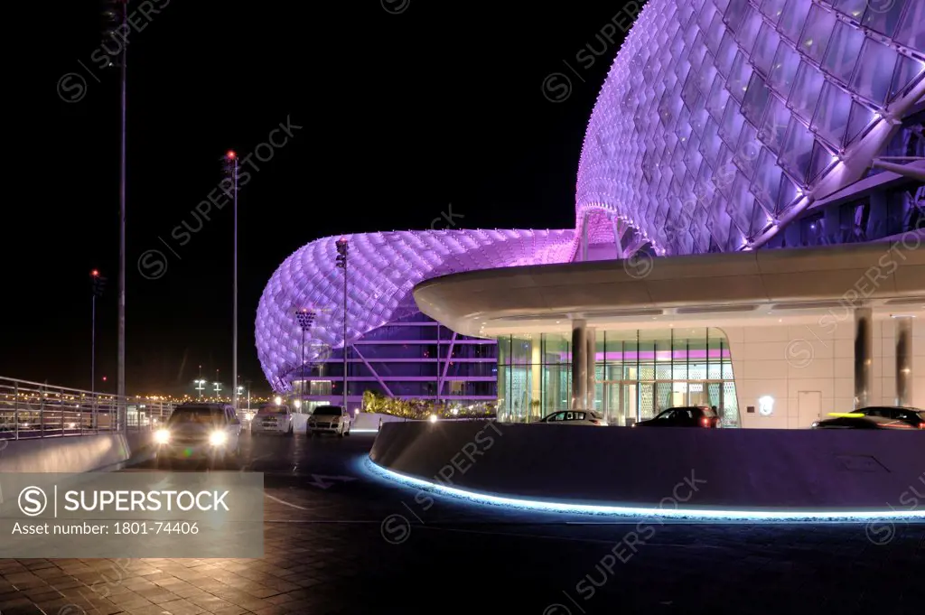 Yas Hotel, Abu Dhabi, United Arab Emirates. Architect: Asymptote, Hani Rashid, Lise Anne Couture, 2010. Outside view of entrance by night with cars passing.