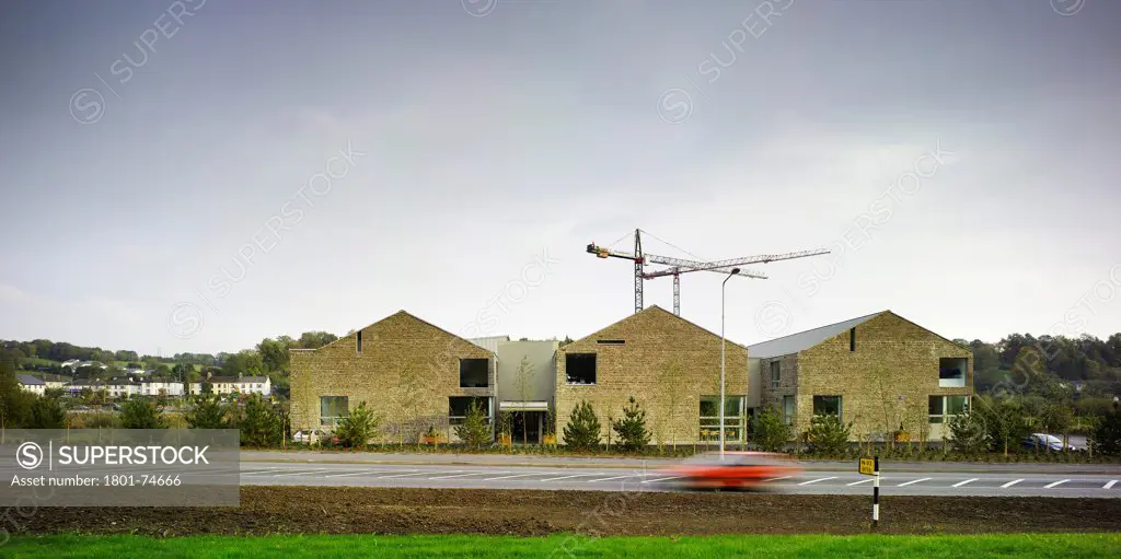 Cavan College, Cavan, Ireland. Architect: McCullough Mulvin , 2006. View of West facade showing road, surrounding landscape and the stone gables of the three blocks.