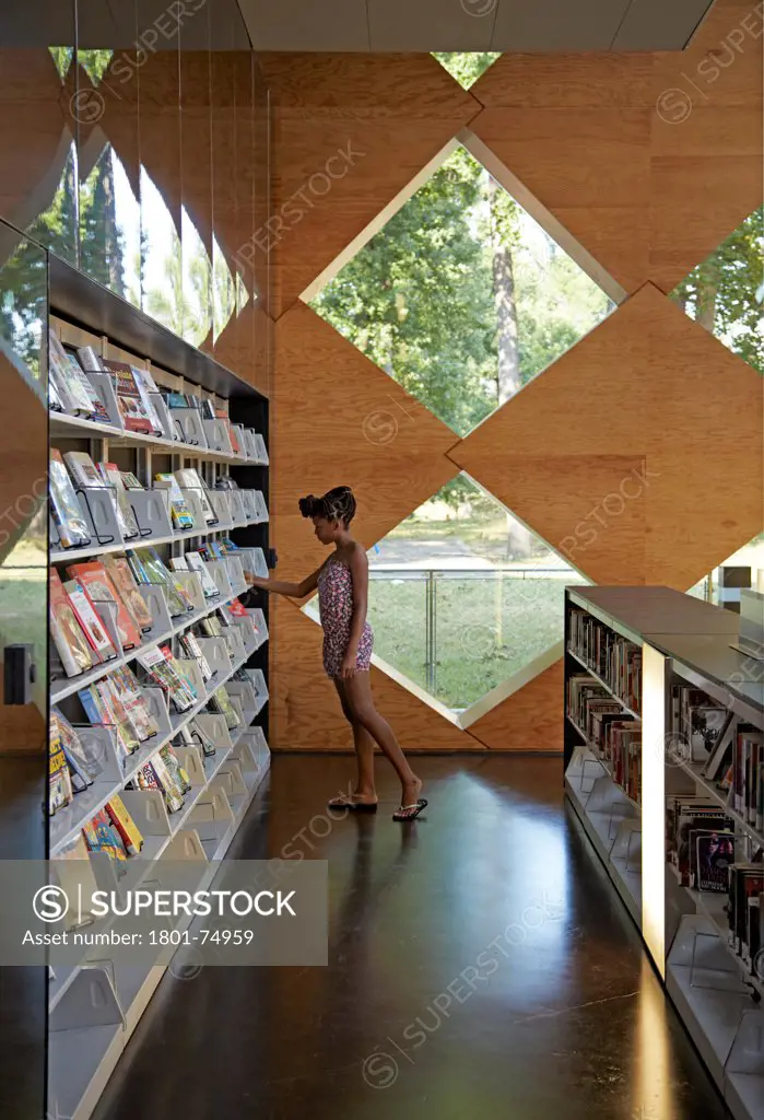 The Francis Gregory Library, Washington, United States. Architect: Adjaye Associates, 2012. Overall interior view on lower level with figure choosing book.