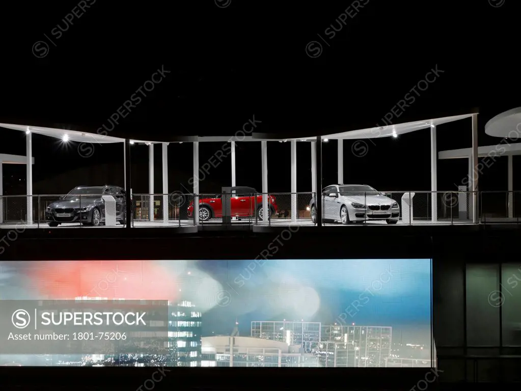 BMW Group Pavilion London 2012, London, United Kingdom. Architect: Serie Architects, 2012. Night shot of structure with cars and graphics.