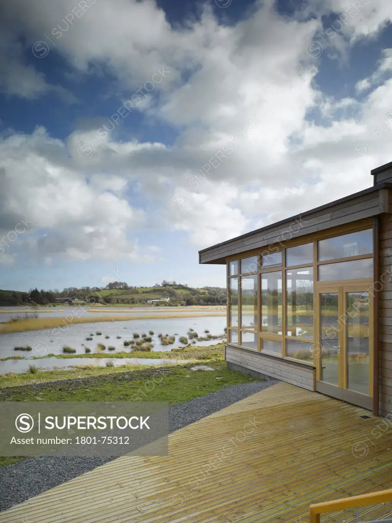 Ballybay Wetland Centre, Ballybay, Ireland. Architect: Solearth Ecological Architecture, 2008. View from decking showing entrance, lake and surrounding landscape.