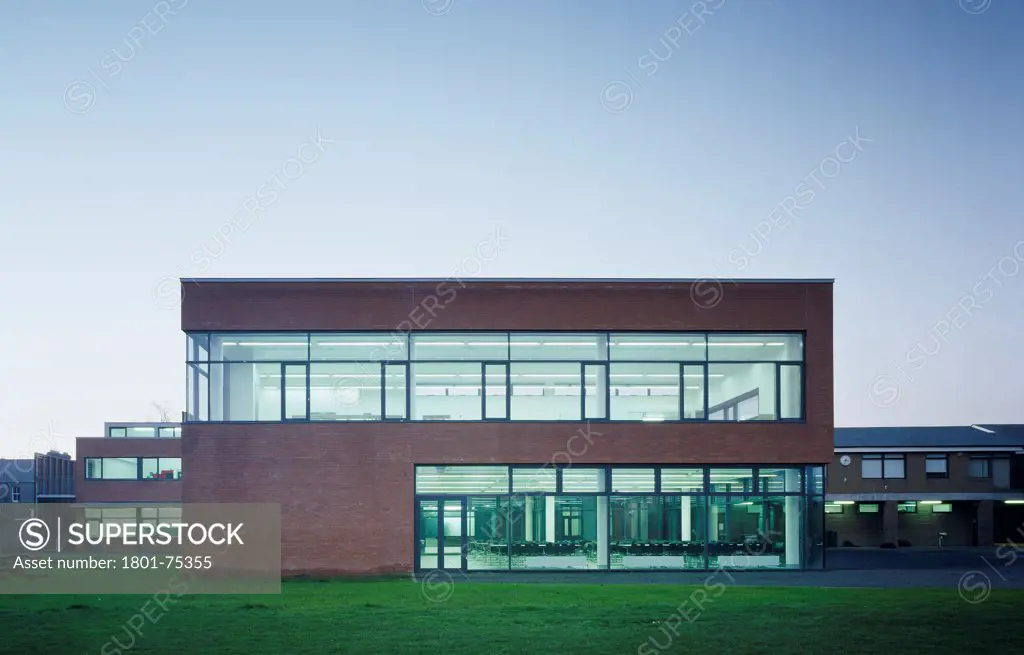Sandford Park School, Ranelagh, Ireland. Architect: DTA Architects, 2007. View of new addition showing brick facade, surroundings, and view to dining room at dusk.
