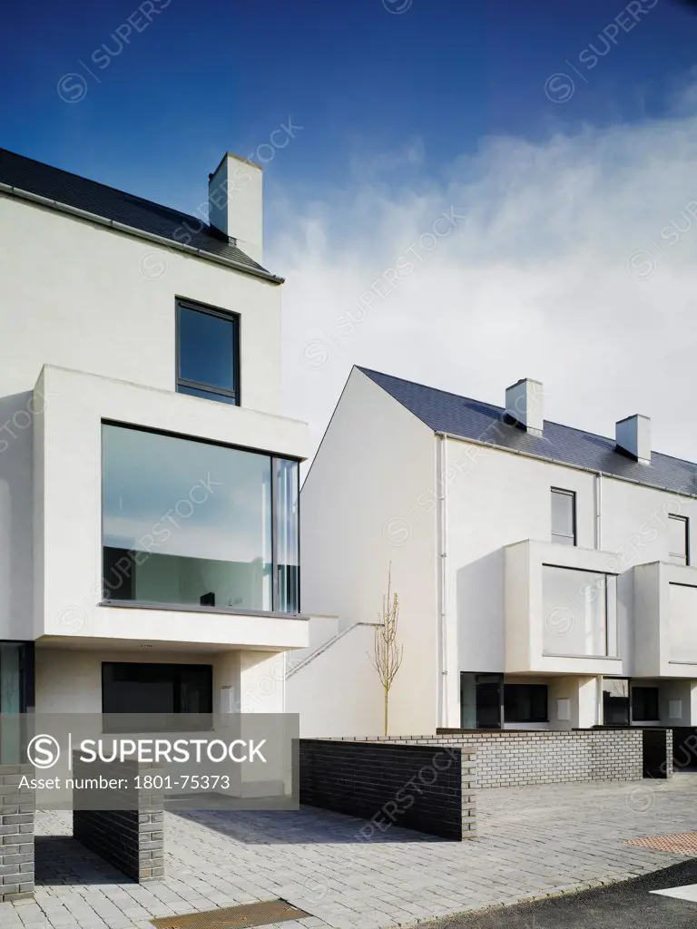Gleann Bhan, Galway, Ireland. Architect: DTA Architects, 2008. View of the end of two terraces showing front elevation and brick wall.