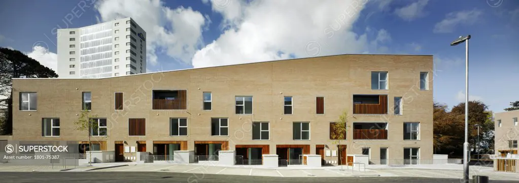 Santry Demesne, Fingal, Ireland. Architect: DTA Architects, 2009. View of facade of housing block from road showing brick building with timber cladding.