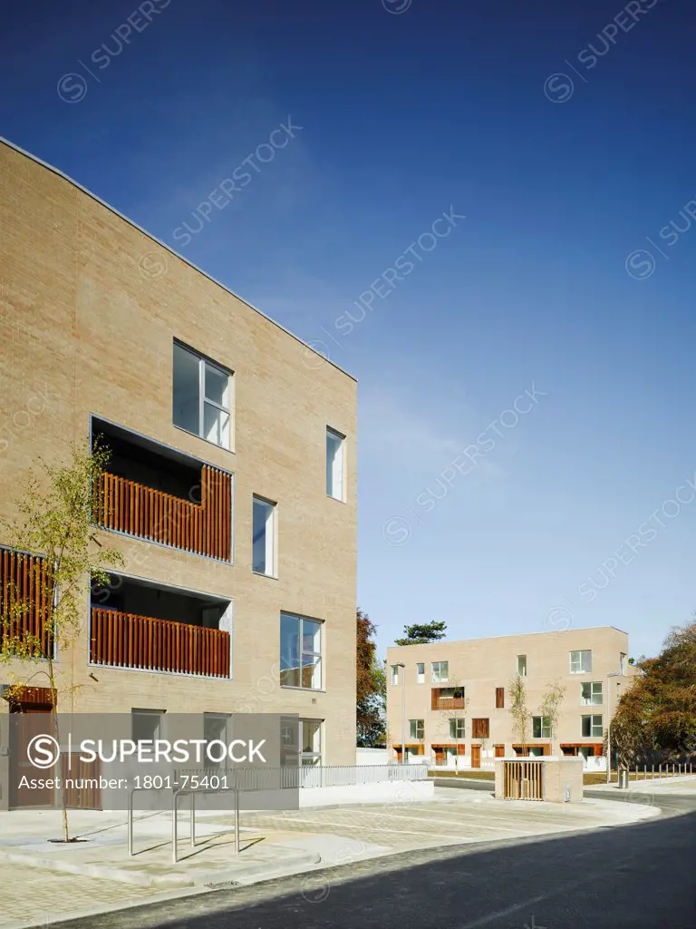 Santry Demesne, Fingal, Ireland. Architect: DTA Architects, 2009. View of development from road showing car park and brick housing block with timber cladding.