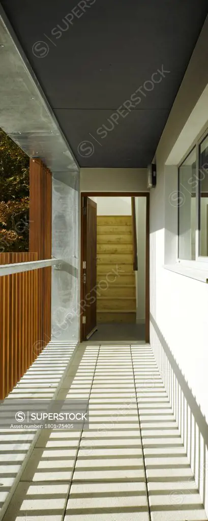 Santry Demesne, Fingal, Ireland. Architect: DTA Architects, 2009. View of access balcony showing light coming through timber balustrade, concrete finishing and view to interior showing staircase.