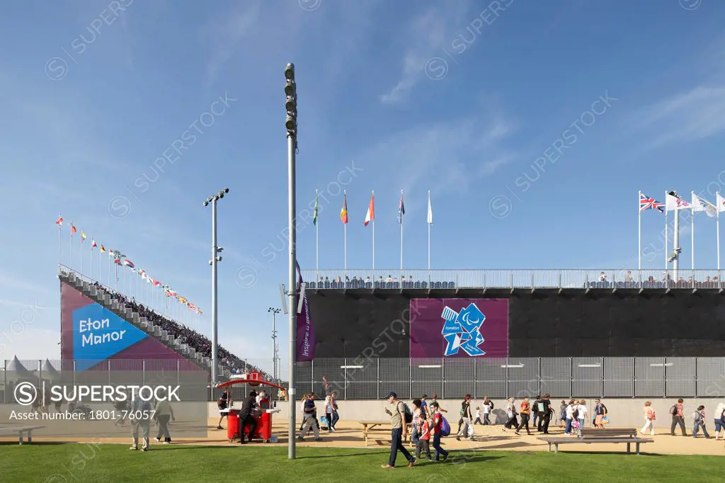 Eton Manor Olympic Park, London, United Kingdom. Architect: Stanton Williams, 2012. Frontal lateral elevation with tribunes, flags and visitors.
