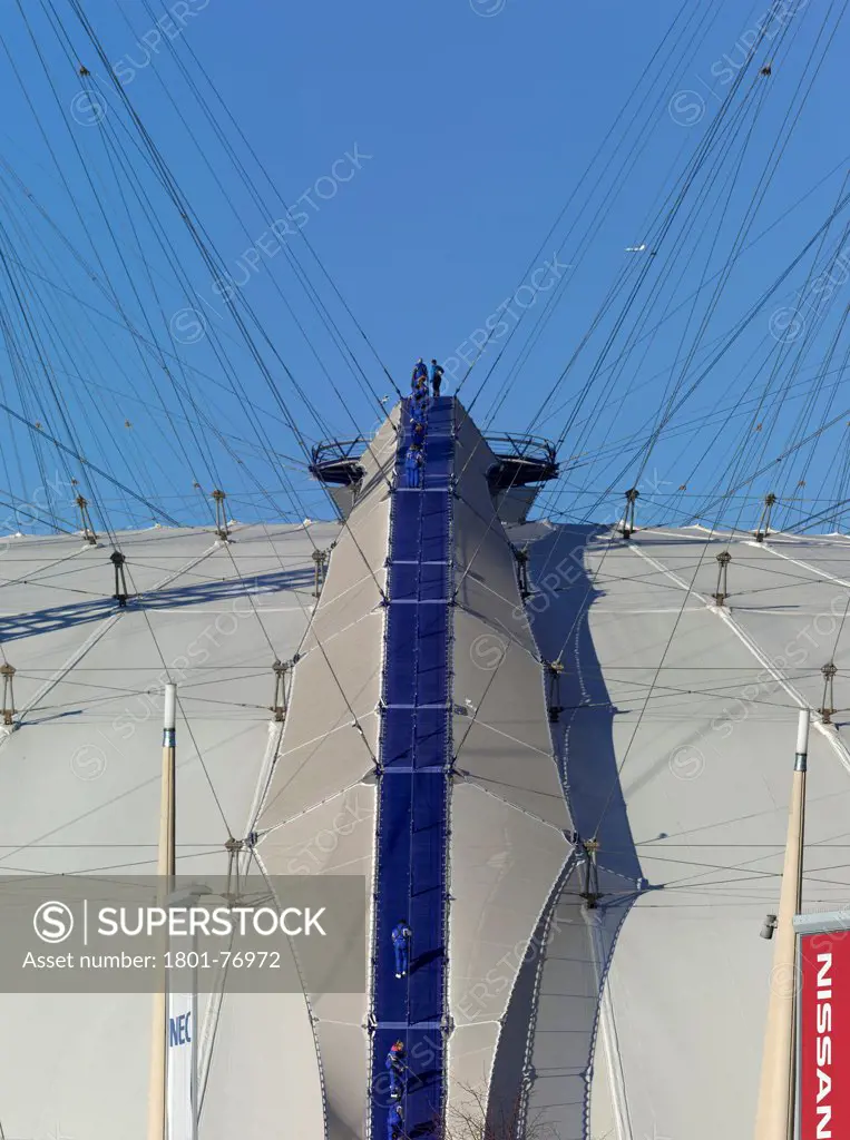 'Up at the O2'- High level walkway over the Millenium Dome, London, United Kingdom. Architect: Rogers Stirk Harbour + Partners, 2012. View from below with figures climbing walkway.