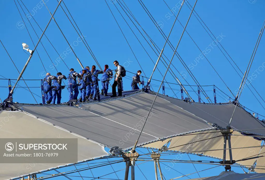 'Up at the O2'- High level walkway over the Millenium Dome, London, United Kingdom. Architect: Rogers Stirk Harbour + Partners, 2012. View from below with figures climbing dome.