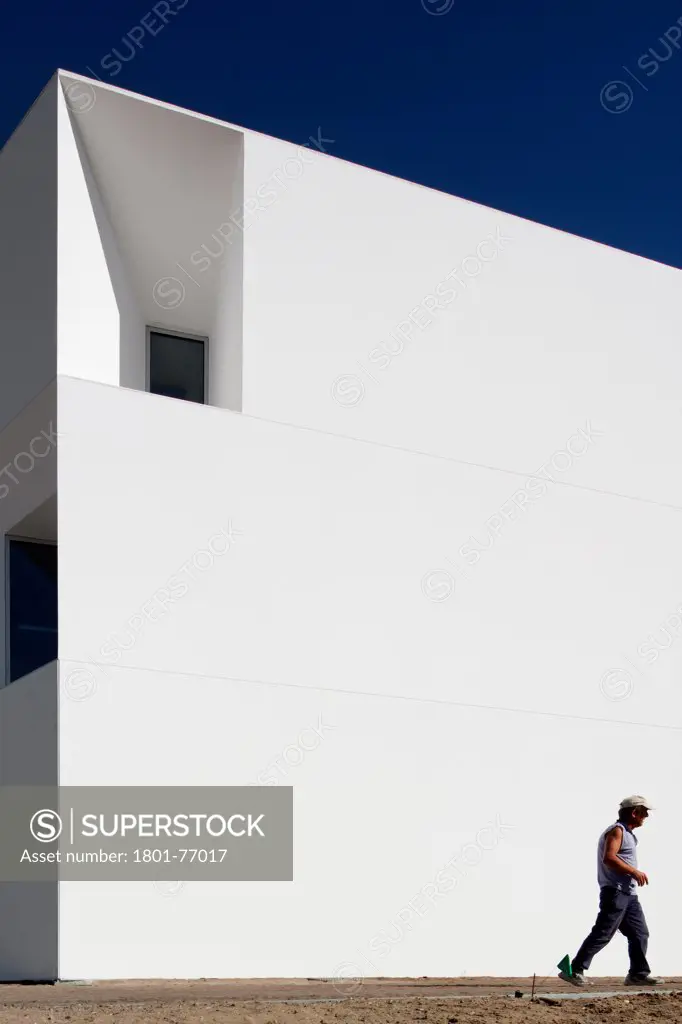 House for Elderly People, Alcaçer do Sal, Portugal. Architect: Francisco Aires Mateus Arquitectos, 2011. View of social housing complex in daylight with person.