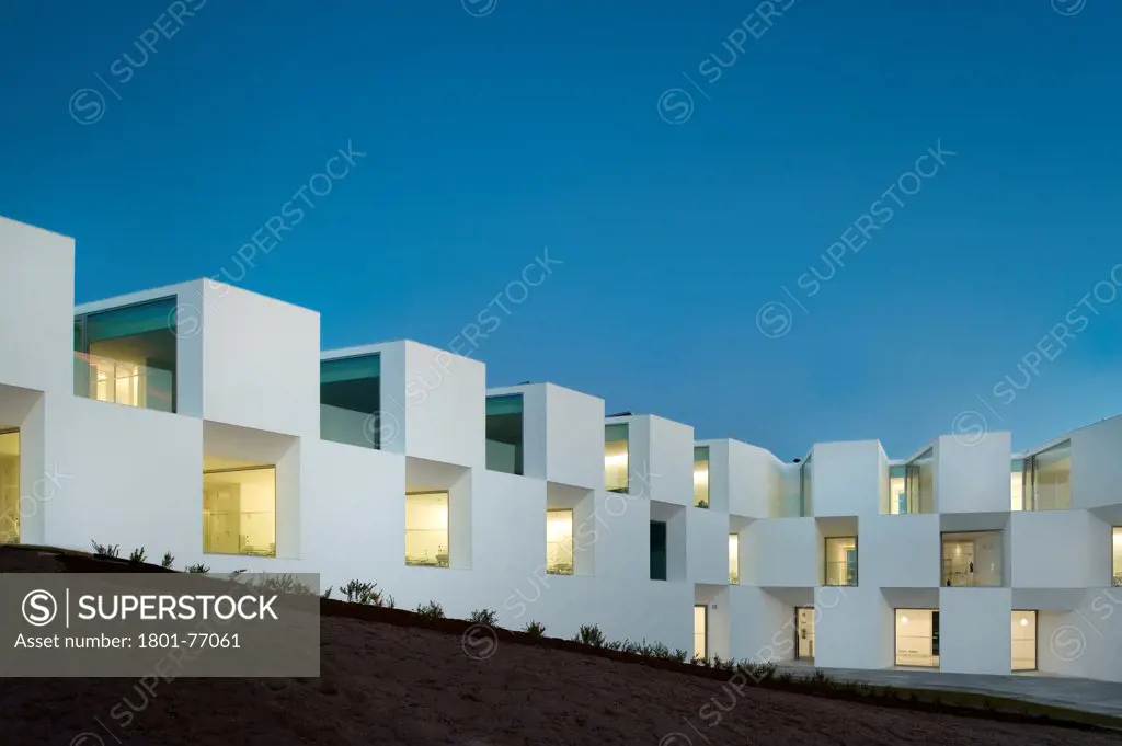 House for Elderly People, Alcaçer do Sal, Portugal. Architect: Francisco Aires Mateus Arquitectos, 2011. View of social housing complex at dusk.