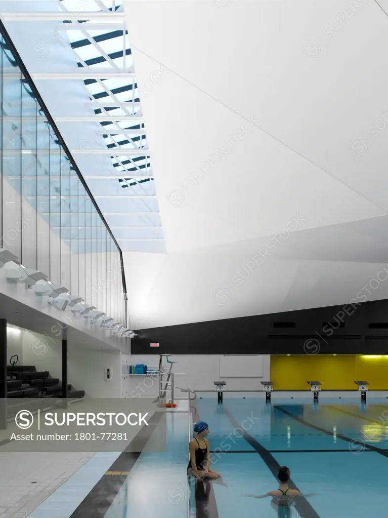 Centre Aquatique, St Hyacinthe, St Hyacinthe, Canada. Architect: Architecture, 2012. View of main pool, bleacher seating, roof light with two swimmers.