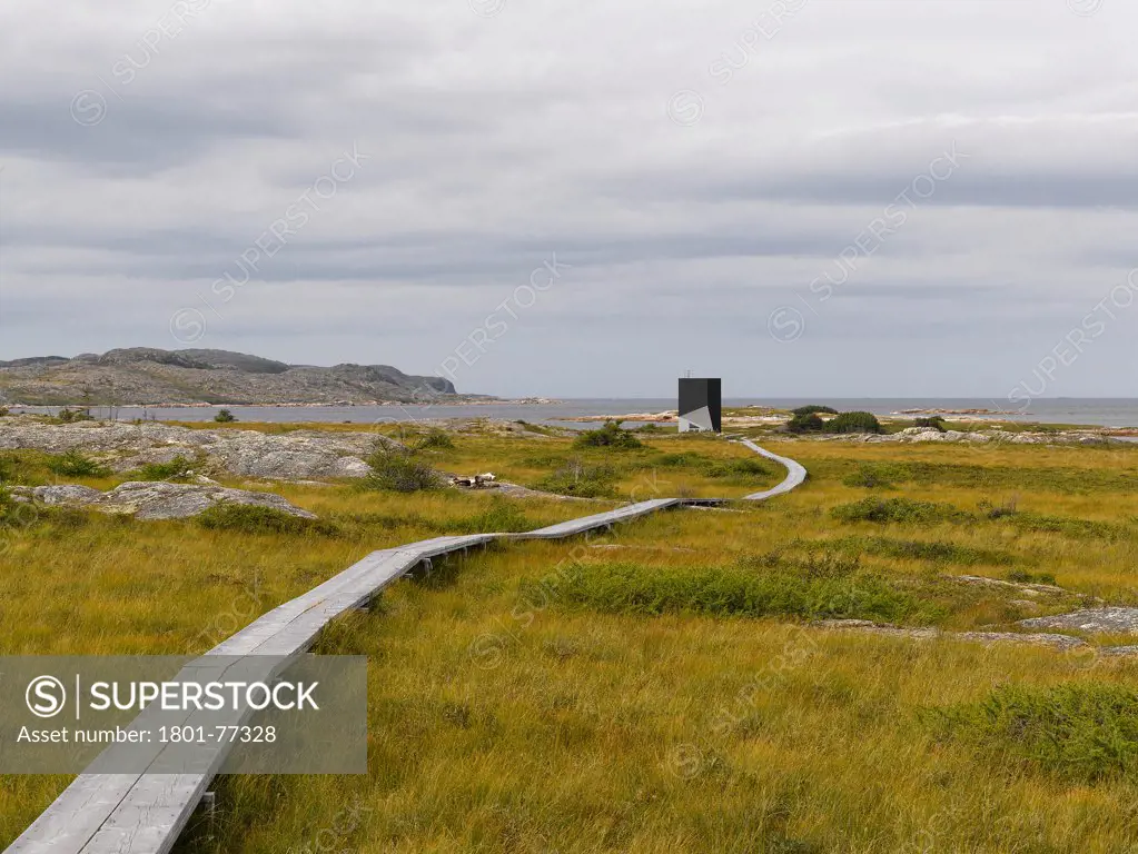 Tower Studio, Fogo Island, Canada. Architect: Todd Saunders, 2011. Distant view across marsh, with ribbon walkway.
