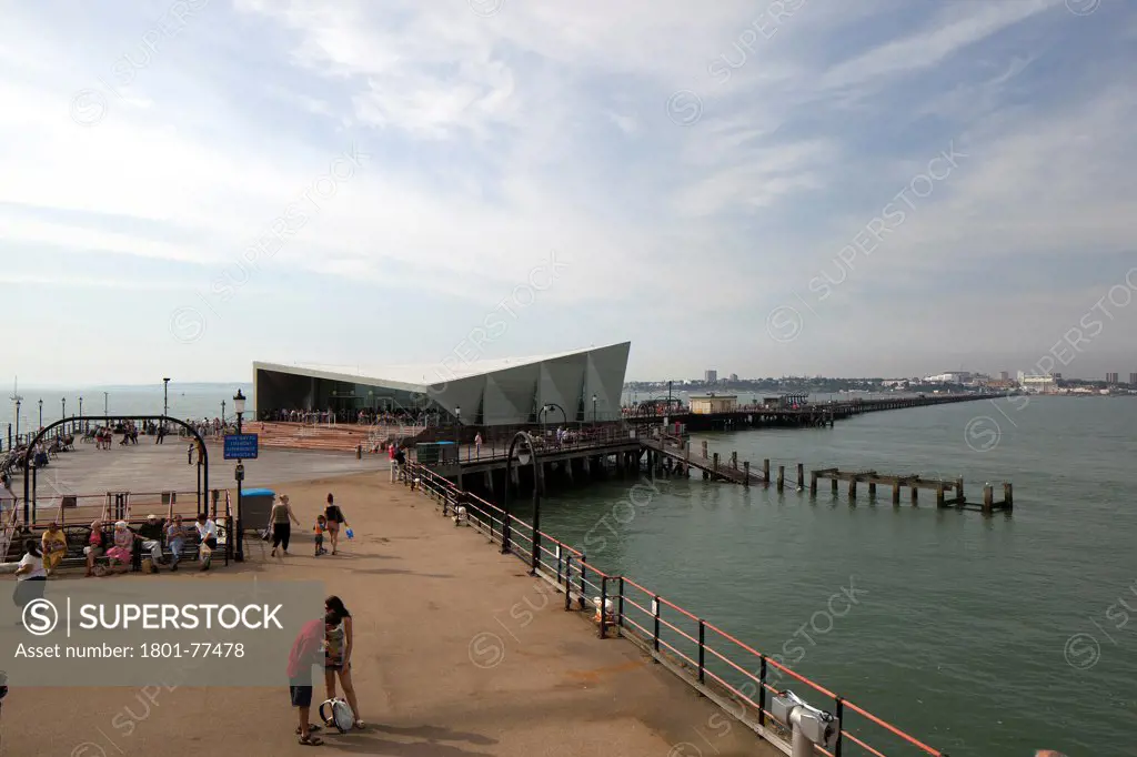 Southend Pier Cultural Centre, Southend, United Kingdom. Architect: White Architects, 2012. Main exterior with people taken from the lifeboat station. Showing the full length of the pier and Southend.