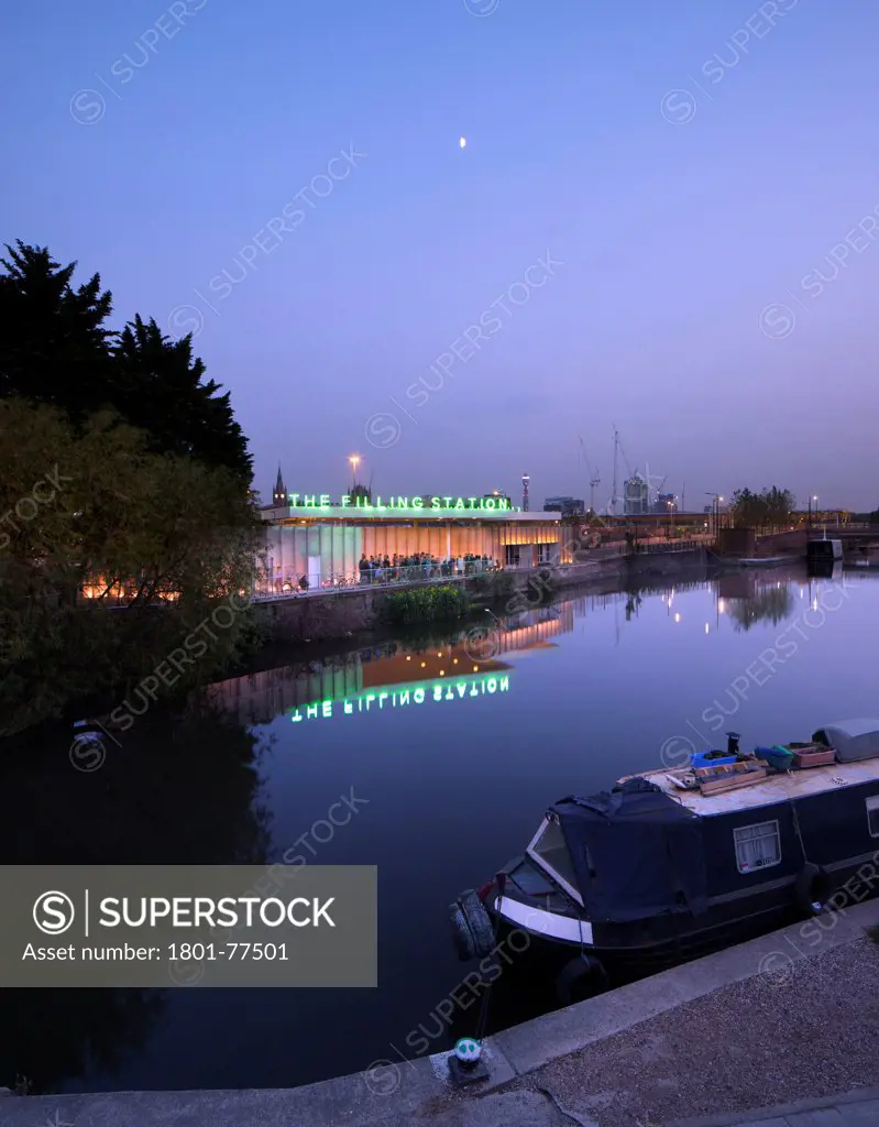 The Filling Station, London, United Kingdom. Architect: Carmody Groarke, 2012. Night time exterior looking across the Regents Canal, with a barge in the foreground.