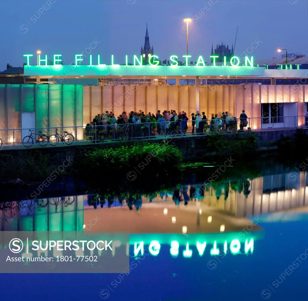 The Filling Station, London, United Kingdom. Architect: Carmody Groarke, 2012. Night time exterior looking across the Regents Canal with lots of customers.