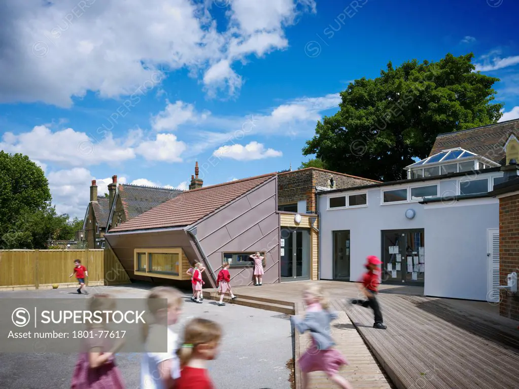 Dulwich Village Infant School, London, United Kingdom. Architect: Cazenove Architects, 2012. Playground view of extension, school children playing.