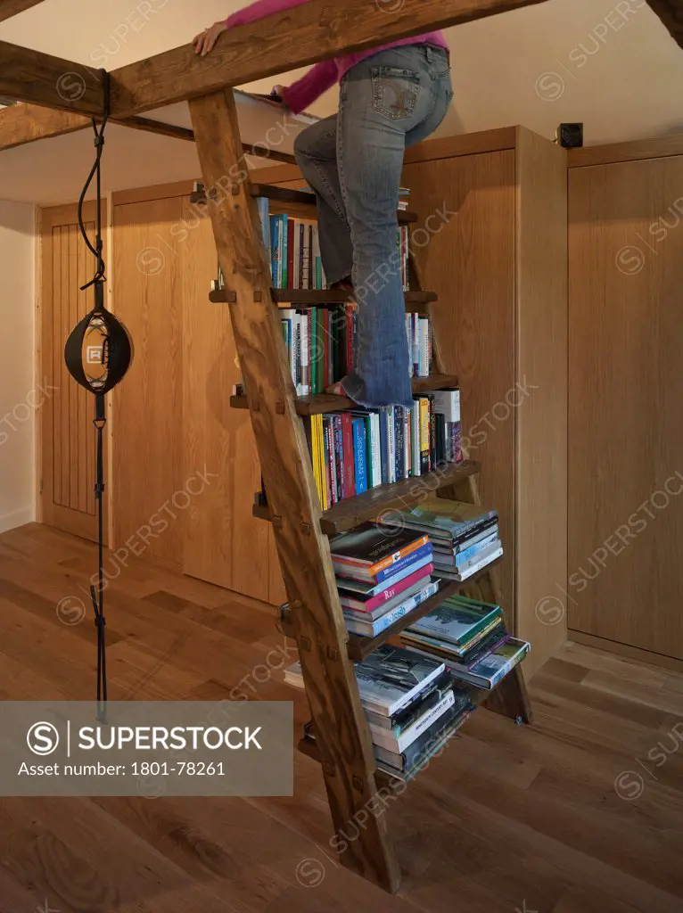 Garden Office, Berkhamsted, United Kingdom. Architect: SDP Design, 2012. Interior room detail showing person climbing bookcase ladder and punch ball to background.