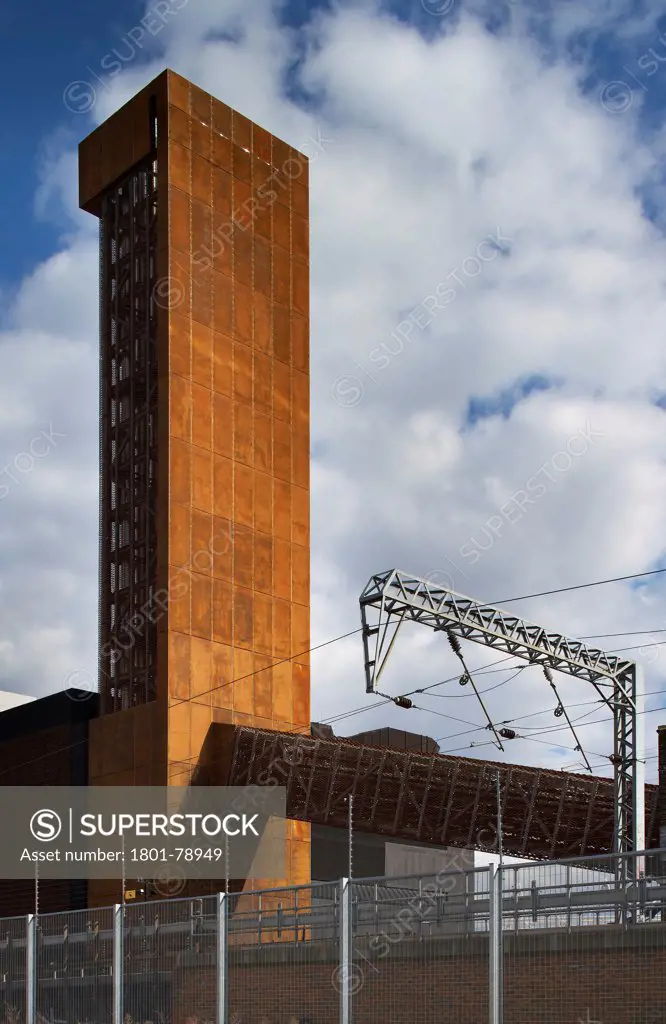 Energy Centre, London, United Kingdom. Architect: John Mcaslan & Partners, 2011. Bold Corten Clad Chimney,Conveyor Duct And Railway Track.