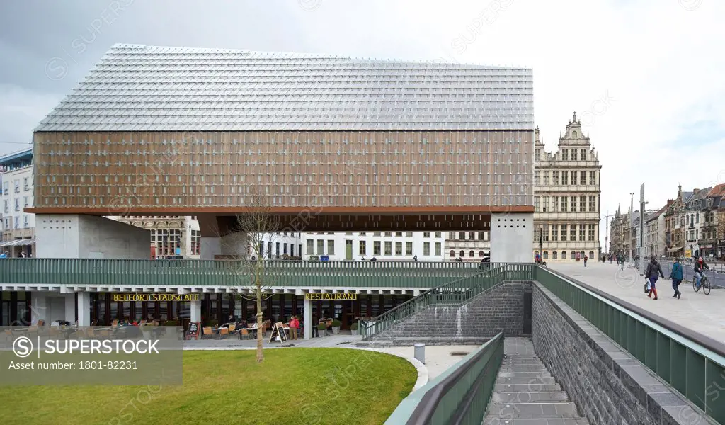 Ghent Market Hall, Ghent, Belgium. Architect: Robbrecht and Daem + Marie-Jose Van Hee, 2013. Lateral view of Market Hall with landscaped green and brasserie below.
