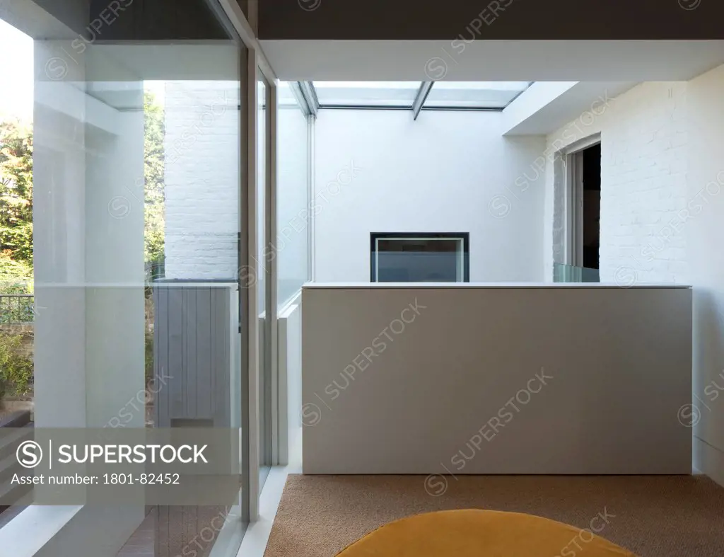 The Cut And Fold House, Twickenham, United Kingdom. Architect: Ashton Porter Architects, 2011. Interior view looking off indoor balcony into double-height glass covered kitchen area.