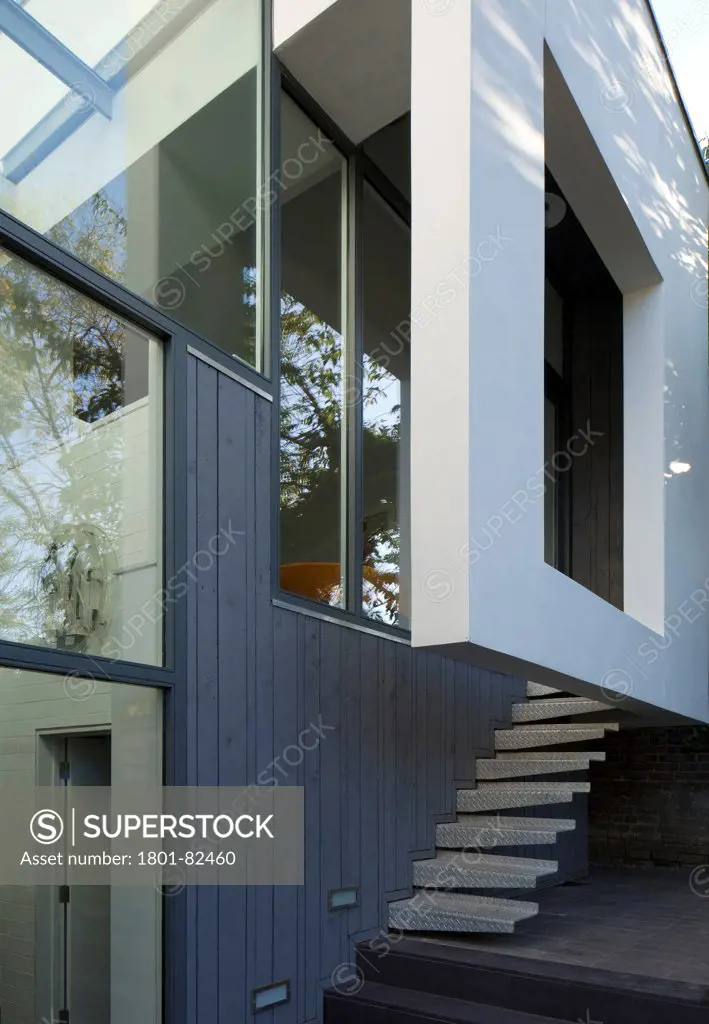 The Cut And Fold House, Twickenham, United Kingdom. Architect: Ashton Porter Architects, 2011. Exterior detail showing the corner of the overhanging extension and metal staircase from patio.