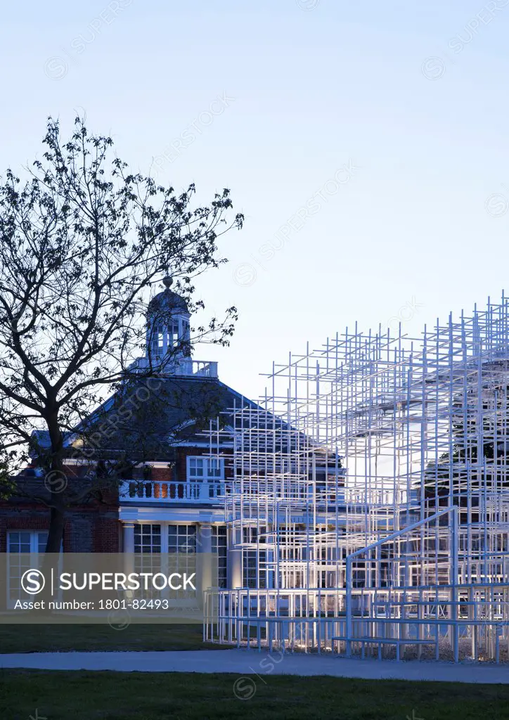 Serpentine Pavilion 2013, London, United Kingdom. Architect: Sou Fujimoto', 2013. Juxtaposition between the glowing pavilion and gallery building at dusk.